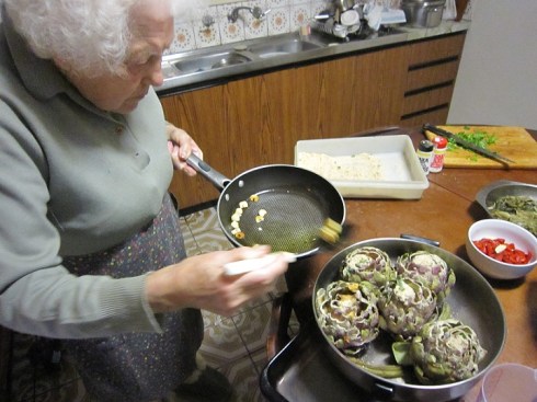 Nonna pours garlic over artichokes